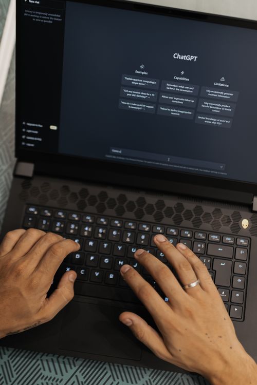 Hands typing on a laptop displaying the ChatGPT AI interface